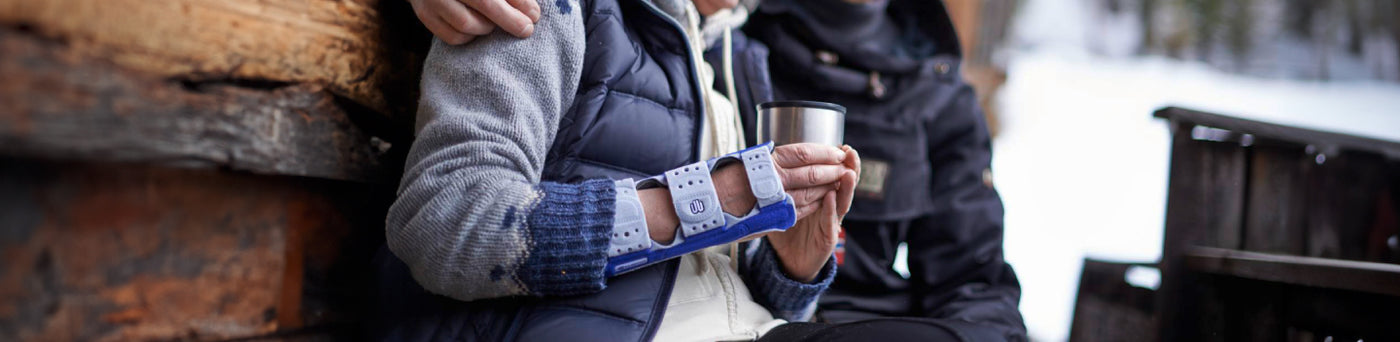 Woman sitting outside in the winter with her husband drinking hot coffee in a ManuLoc wrist brace