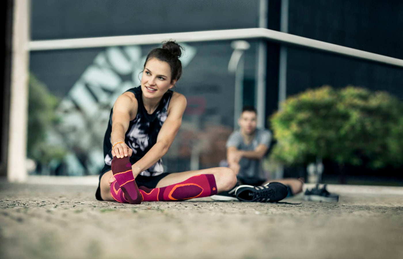 Woman sitting on the floor and stretching her hamstrings in Bauerfeind's Performance Socks as part of her cooldown exercise routine