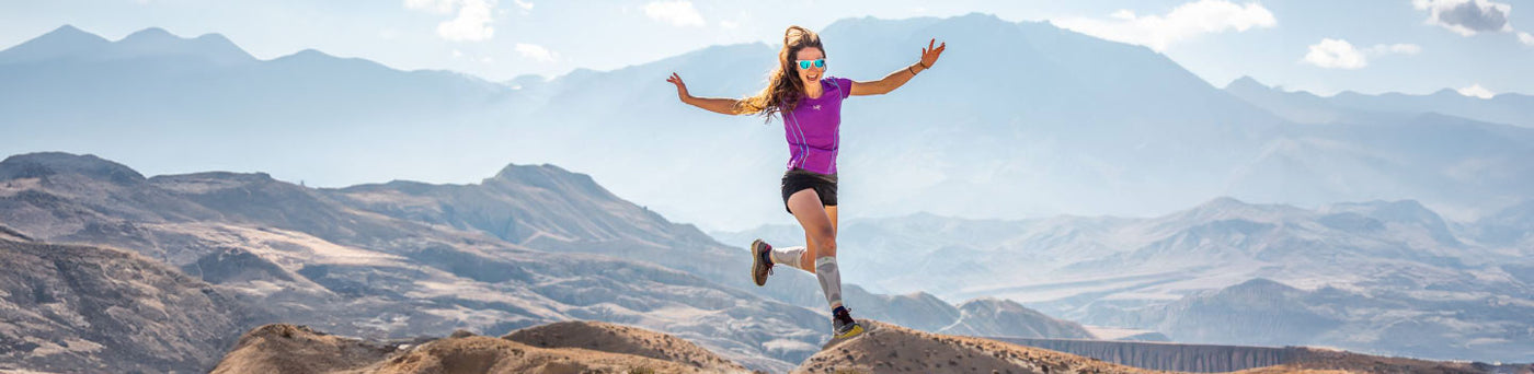 Woman running along the top of a mountain in Bauerfeind's sports compression socks
