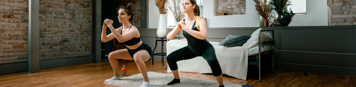 two women performing bodyweight squats in their living room