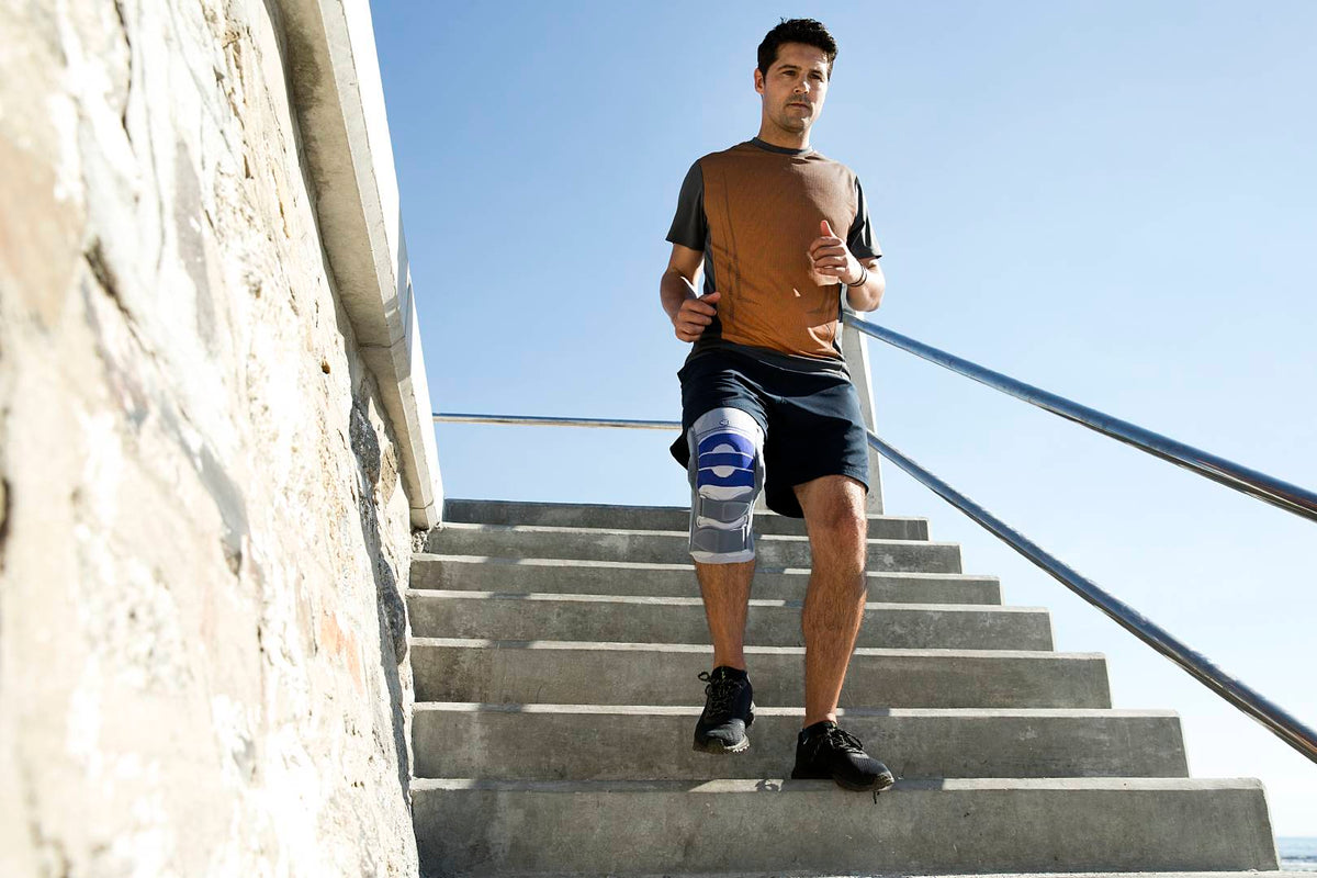 Man jogging down the stairs wearing a SofTec Genu, the best brace for cruciate ligament tears and collateral ligament injuries