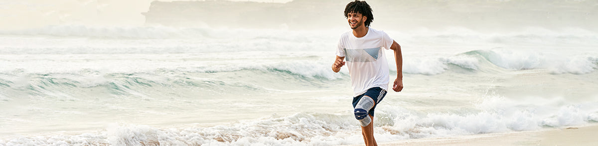 Man running along the beach. How long should you wait to run after a torn ACL injury