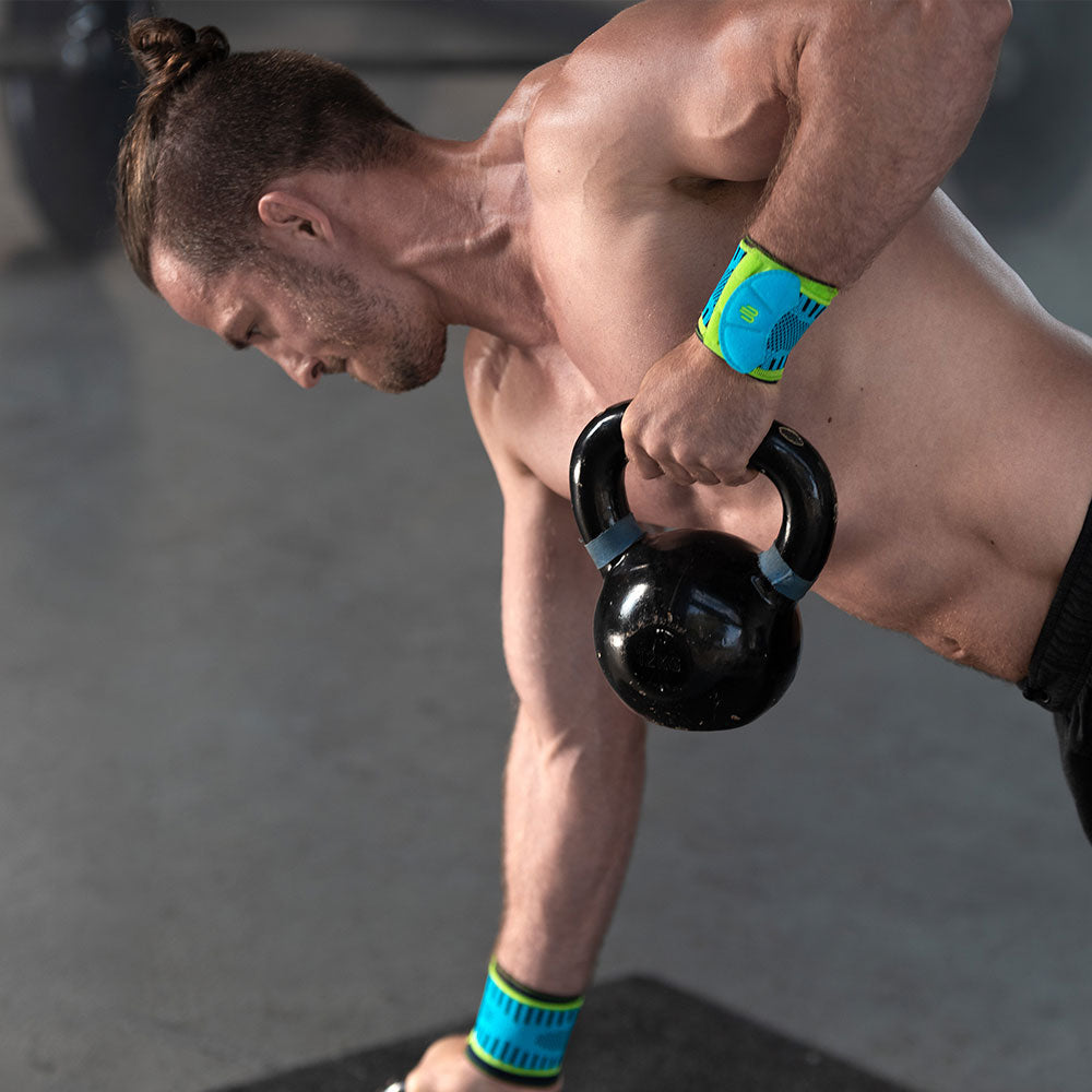 Man wearing weightlifting wrist straps lifting Kettle Bells
