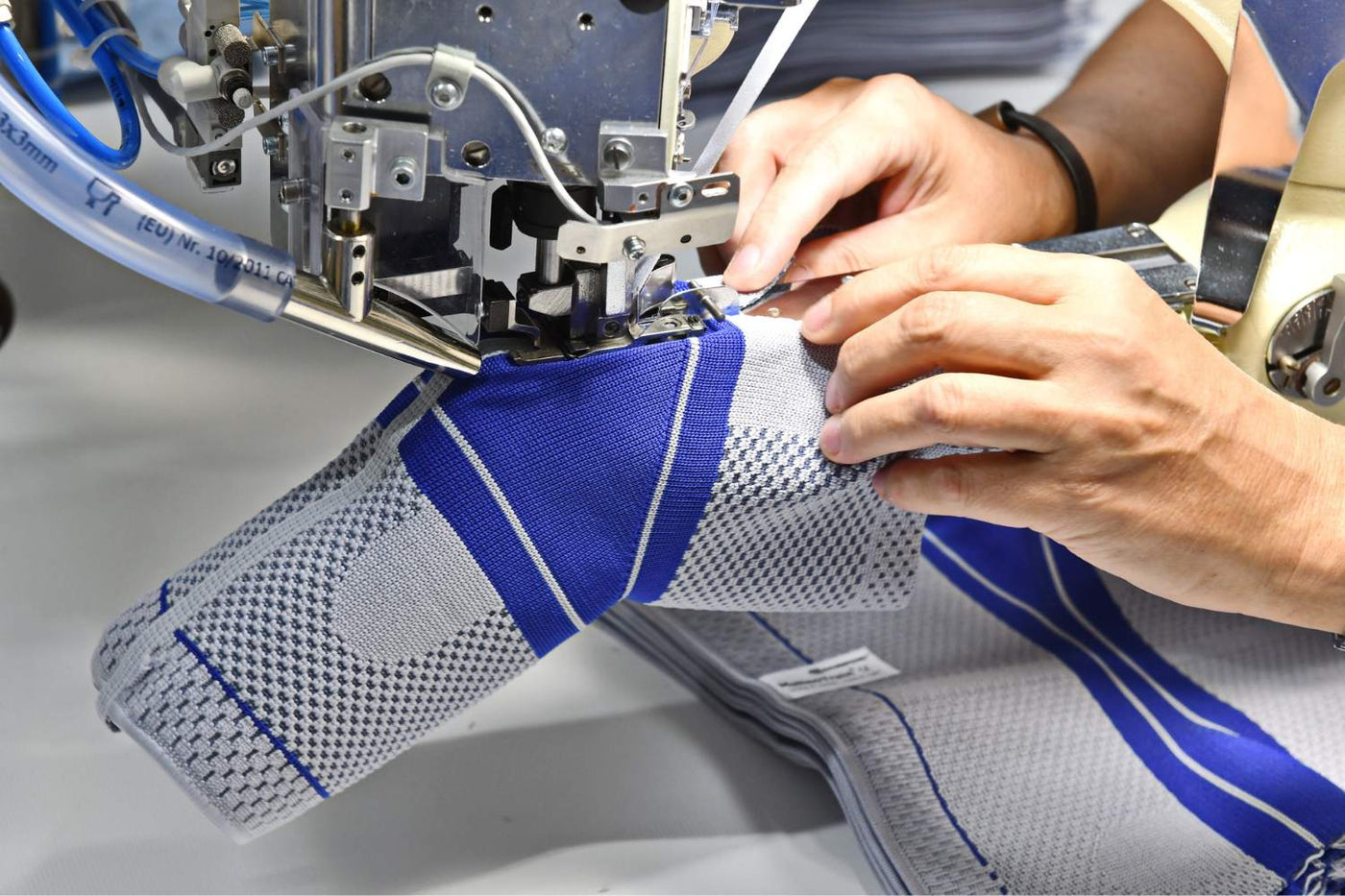 Bauerfeind employee machine-sewing one of patented Omega pads into a GenuTrain Knee Brace