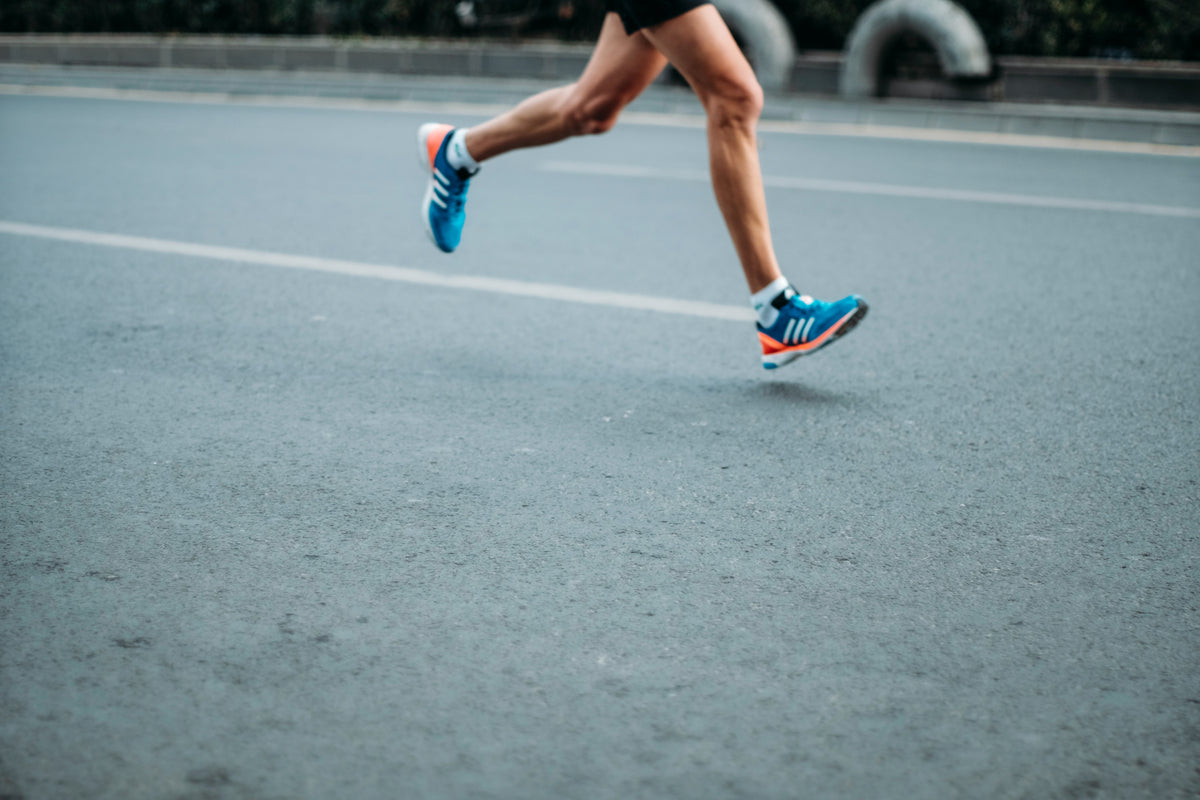 A mans legs, from the hips down. He is running down the street. How to prevent knee injury.