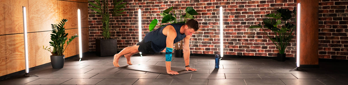 Thomas Roehler performing the plank taps exercise for core and arm strength while wearing Bauerfeind's Sports Elbow Support