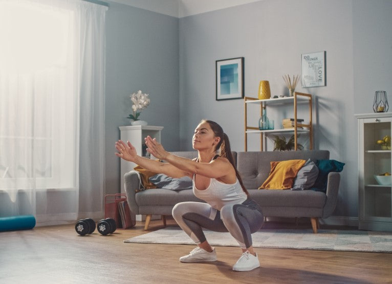 Woman performing the sit to stand exercise in her living room to improve her core strength